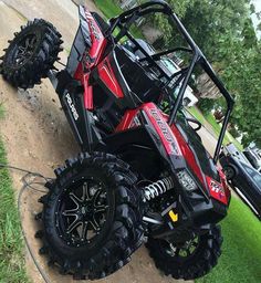 a red and black polaris rzr xp4 is parked in the grass