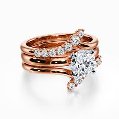 two rose gold wedding rings with diamonds on each band and an oval shaped diamond in the center