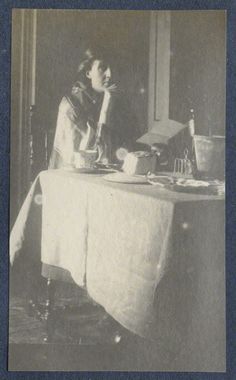 an old black and white photo of a woman sitting at a table