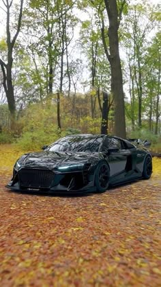 a black sports car parked on the side of a road in front of some trees