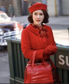 a woman wearing a red coat and holding a red purse