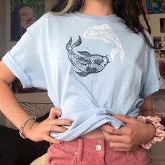 a woman wearing a blue shirt with a whale on it's chest and pink shorts