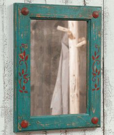 an old mirror hanging on the side of a white wooden wall next to a window