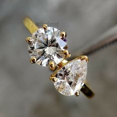 two pear shaped diamond engagement rings sitting on top of each other