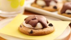 cookies with chocolate and cream on top are sitting on a yellow napkin next to a glass of milk