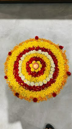 a person standing in front of a flower arrangement with a candle on the floor next to it