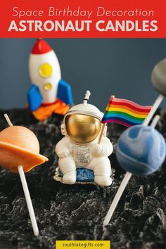 space birthday decoration with astronaut candles and cake toppers in the shape of rockets, planets, and rocket ship