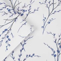 the wallpaper is white and has blue flowers on it, as well as branches