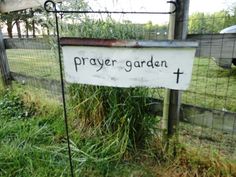 a sign that says prayer garden on it in front of a fenced in area