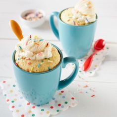 two blue mugs filled with ice cream and sprinkles on a table