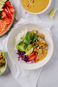 two bowls filled with different types of food on top of a white cloth next to each other