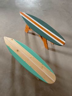 two surfboards sitting on top of each other in a room with concrete flooring