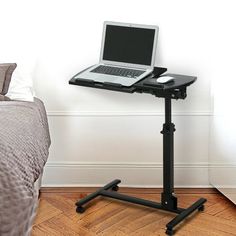 a laptop computer sitting on top of a black stand in front of a white wall