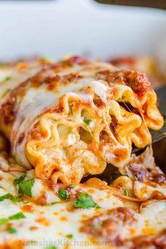 a close up of a plate of food with pasta and sauce on it, being held by a fork