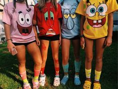 three girls in matching shirts and shorts standing next to each other with their faces painted on them