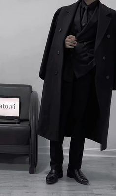 a man in a suit and tie standing next to a black chair with a sign on it