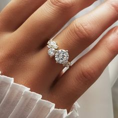 a woman's hand with a diamond ring on top of her finger and the other hand holding an engagement ring