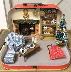 an open suitcase filled with furniture and christmas tree in front of a small fire place