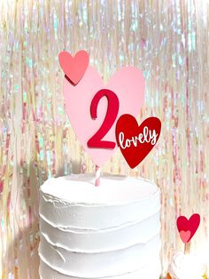 two hearts on top of a white cake with pink frosting and the number twenty