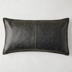 a black leather pillow sitting on top of a white wall