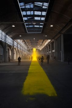 people are walking in an empty building with yellow lines