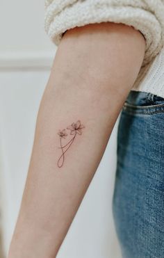 a woman's arm with a single flower tattoo on the left side of her arm