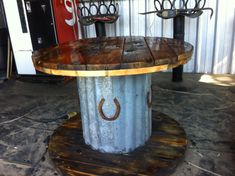 an outdoor table made out of metal and wood with horseshoes on the top, sitting in front of a building