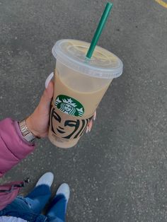 a person holding up a starbucks drink with a green straw in it's cup