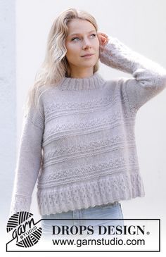 a woman wearing a gray sweater and jeans posing for a photo with her hand on her head