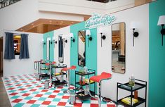 the interior of a barbershop with chairs and tables in front of mirrors on the wall