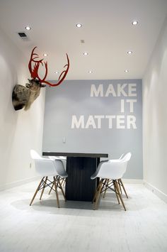 a dining room table with chairs and a deer head mounted to the wall