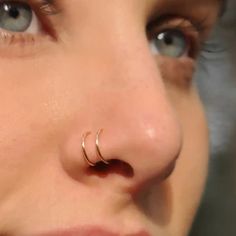 a close up of a person with a nose ring on her nose and piercing in the middle