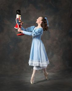 a woman in a blue dress is holding a nutcracker and looking up to the sky