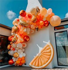 an orange and white balloon arch on the side of a building