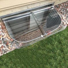 an open window on the side of a building with rocks and gravel around it, in front of a house