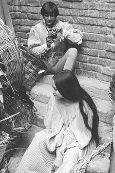 two women sitting on the steps next to each other and one is looking at her cell phone