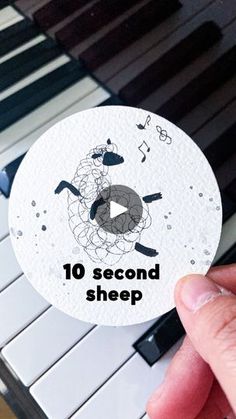 someone is holding up a sticker with the words 10 second sheep on it in front of a piano keyboard