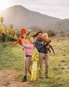 three adults and two children are standing in the grass with one child holding a stuffed animal