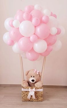 a teddy bear in a basket with balloons