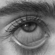 the eye of a man with very long lashes and no makeup is seen in this black and white photo