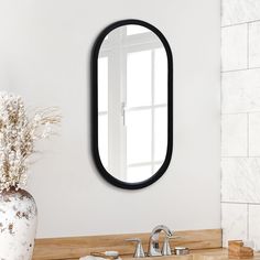 a bathroom sink with a mirror above it and a vase on the counter next to it