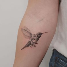 a small hummingbird tattoo on the left arm and right arm, with a flower in it's beak