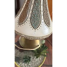 a white lamp sitting on top of a table next to a plate filled with flowers