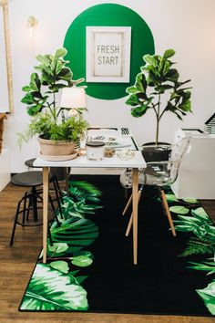 a green and white room with plants on the wall, chairs and rug in front of it