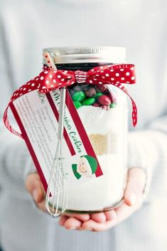 a person holding a jar with candy in it and a red bow on the top