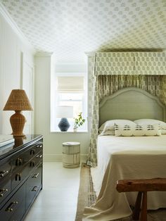 a bed sitting next to a dresser in a room with white walls and flooring