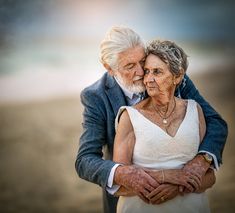 an older couple embracing each other on the beach