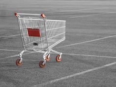 an empty shopping cart sitting in the middle of a parking lot with no one inside