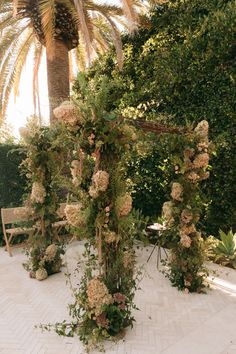 an outdoor wedding ceremony with flowers and greenery