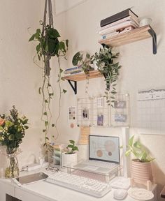 a white desk topped with a laptop computer next to a potted plant on top of a wooden shelf